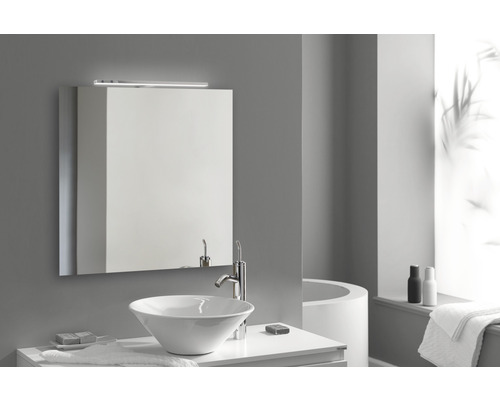 Ljust badrum med vitt tvättställ, tvättskål, spegelskåp och belysning