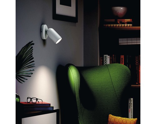 Vardagsrum med grön fåtölj och vit vägglampa