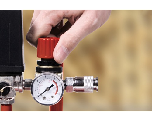Hand justerar tryckregulator på en kompressor