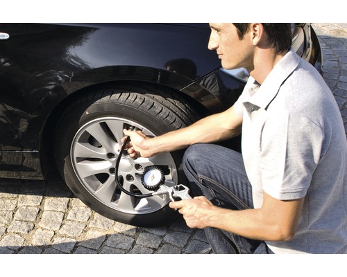 Man kontrollerar däcktrycket på en bil med en däcktrycksmätare