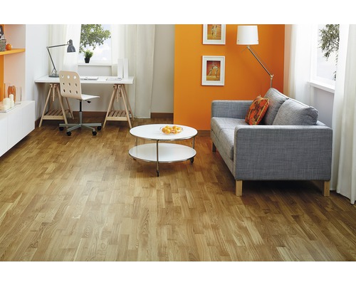 Vardagsrum med ljust trägolv, soffa, bord och skrivbord