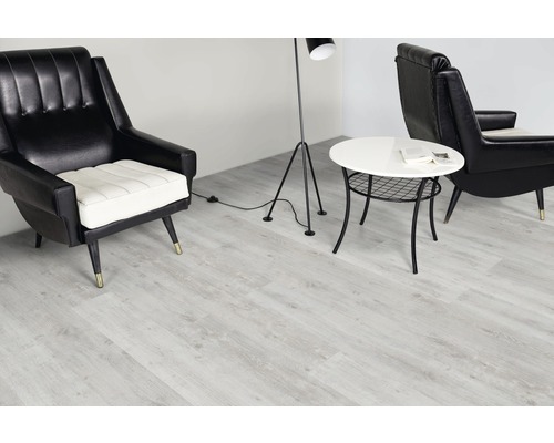 Vardagsrum med ljust vinylgolv, fåtöljer, golvlampa och sidobord