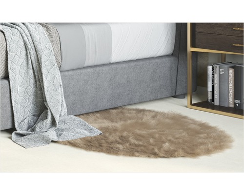 Dekorativ sovrumsmiljö med säng, sidobord och en oval matta