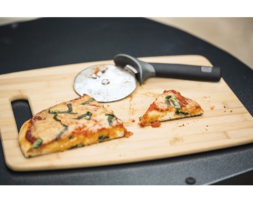 Två pizzabitar och pizzaskärare på skärbräda i trä