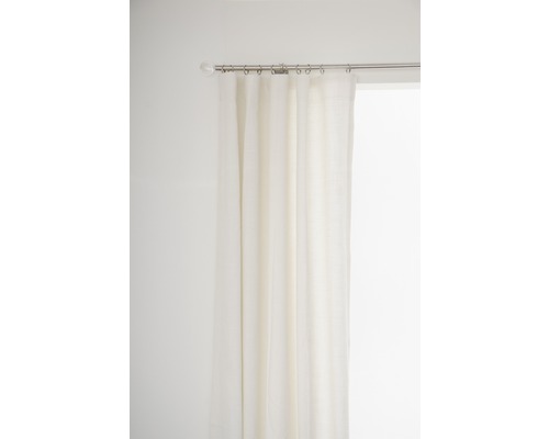 Gardin av tyg på en gardinstång med ringar framför ett fönster.