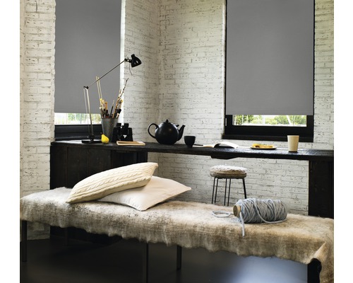 Dekorativt rum med grå rullgardiner för fönstren och ett bord med olika föremål.