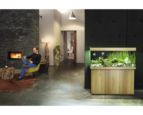 Vardagsrum med akvarium, öppen spis och läsande man