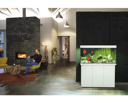 Vardagsrum med akvarium och sittande man vid eldstaden.