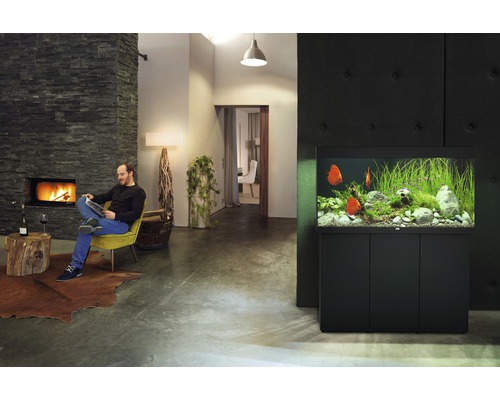 Vardagsrum med akvarium, öppen spis och läsande man