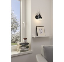Vardagsrum med fönster, bokstapel och vägglampa