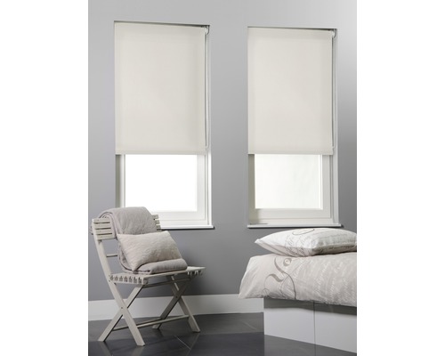 Två fönster med monterade rullgardiner i ett sovrum.