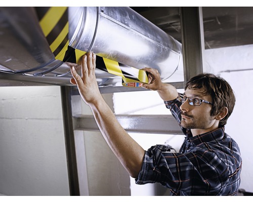 Man fäster varnings tejp på ett ventilationsrör.