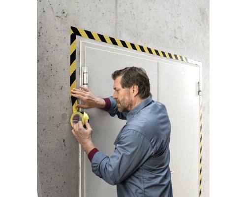 Man applicerar varningsmarkeringstejp på en dörr