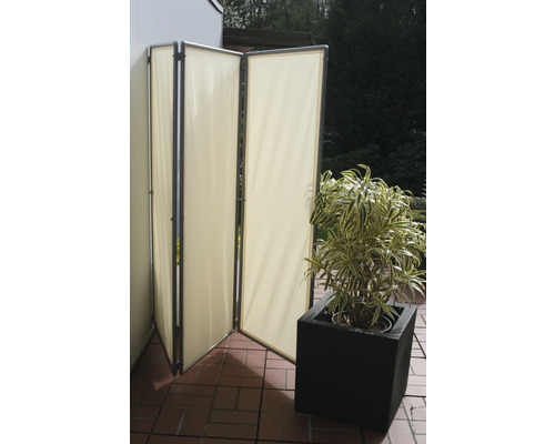 Vikbar skärmvägg i tyg bredvid en krukväxt på en terrass.