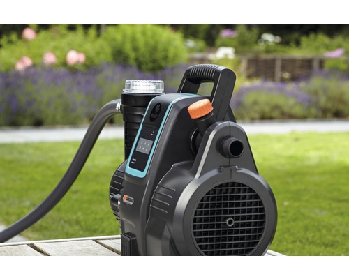 Trädgårdspump med slang på ett träbord i trädgården