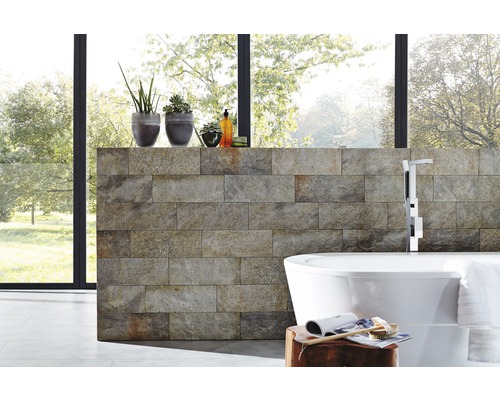 Modernt badrum med naturstensvägg, fristående badkar och krukväxter