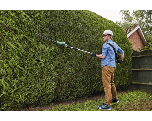 Man klipper häck med en batteridriven häcksax