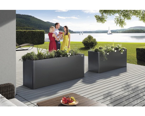 Scen med två planterade rektangulära metalllådor på en terrass med utsikt över en sjö