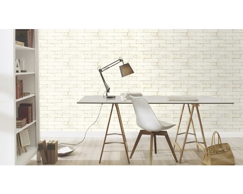 Arbetsrum med bord, stol, lampa och bokhylla framför en vägg med tegel tapet
