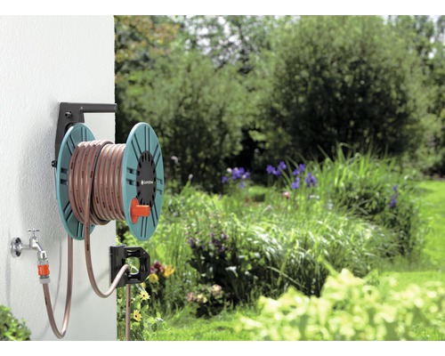 Trädgårdsslang på slangvagn monterad på en vägg