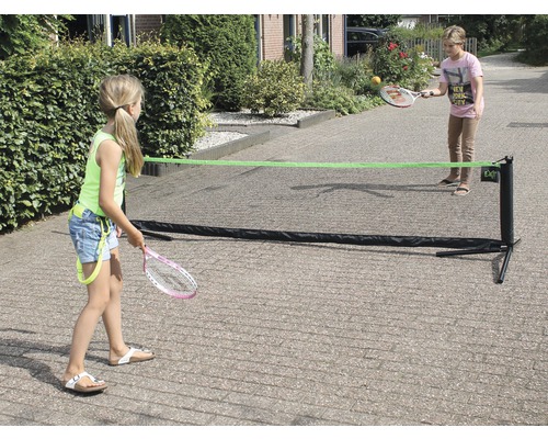 Två barn leker med ett bärbart tennisnät utomhus.