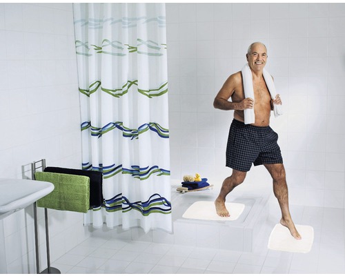 Ljust badrum med duschdraperi, badrumsmattor och en person med en handduk