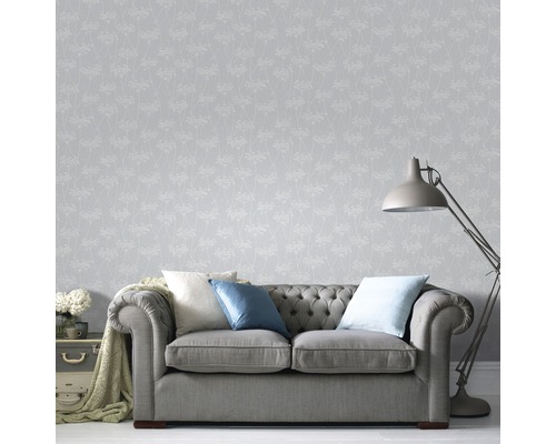 Vardagsrum med grå tapet med blommönster, soffa och golvlampa