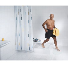 Ljust badrum med duschdraperi och en person som kliver ut ur duschen och håller en handduk.
