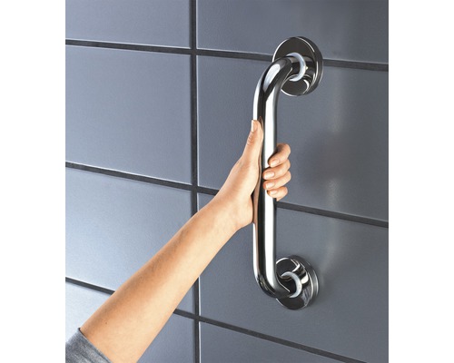 Hand håller ett handtag av rostfritt stål på en vägg