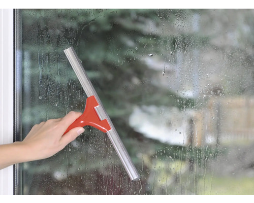 Hand använder en fönsterskrapa på en fönsteryta