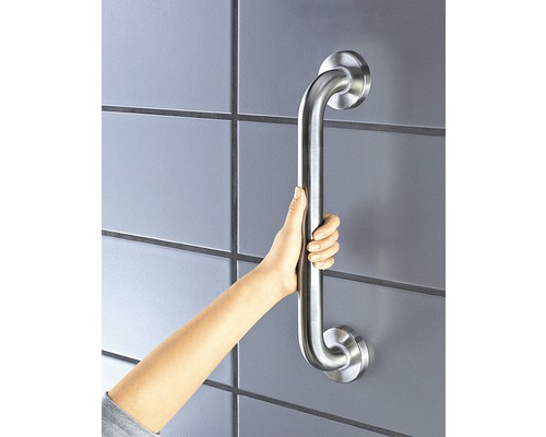 En hand håller ett silverfärgat stödhandtag i ett badrum.