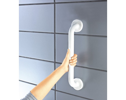 En person håller ett vitt stödhandtag på en vägg.