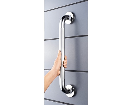 Person håller ett silverfärgat handtag på en vägg