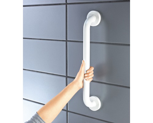 En person håller ett vitt handtag fäst vid en kakelvägg.