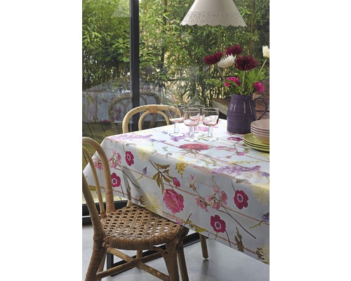 Matbord med blommigt täcke, glas, porslin och blommor i vas