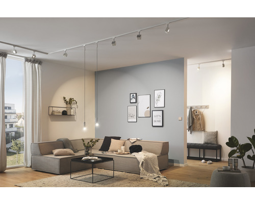 Ljust vardagsrum med takspotlights, soffa, väggdekoration och trägolv