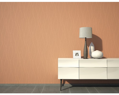 Vardagsrum med mönstrad tapet, byrå, bordslampa och dekoration