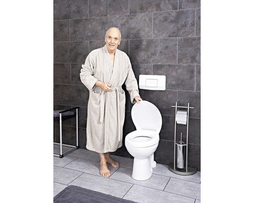Badrum med golvstående toalett och en person i badrock