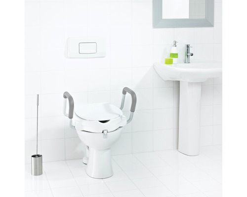 Toalett med toalettförhöjning och handtag i ett ljust badrum