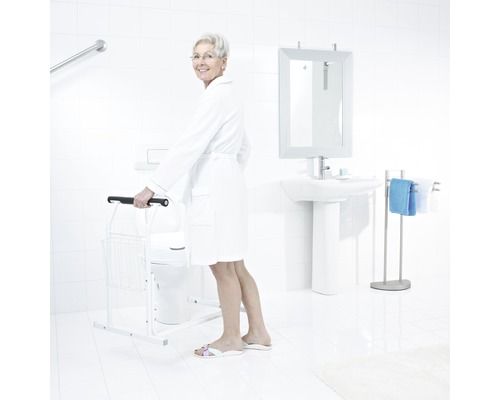 Ljust badrum med toalett, handfat, spegel, handdukshängare och toalettstöd för stöd