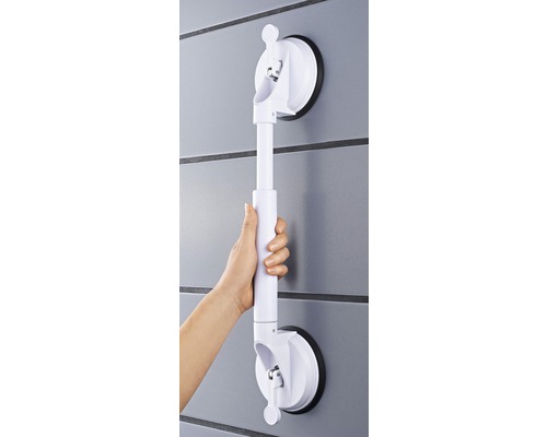 Hand håller ett vitt, justerbart stödhandtag med sugkoppsfäste på en vägg