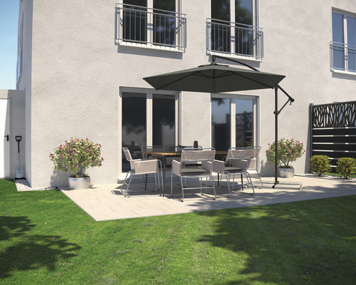 Terrass med trädgårdsbord, stolar och parasoll bredvid ett bostadshus.