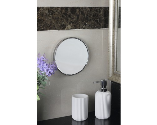 Badrumsscen med rund spegel, tandborstmugg och tvålbehållare