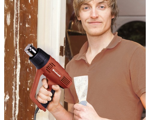 Man med varmluftspistol och spackelspade framför en dörr