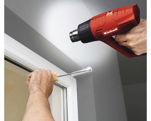 Användning av en Einhell varmluftspistol för att ta bort gammal färg från en fönsterkarm.