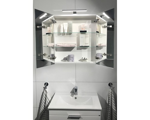 Spegelskåp med öppna dörrar, glashyllor och belysning ovanför ett handfat