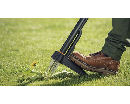 Person använder en ogrässtickare i trädgården för att ta bort maskrosor.