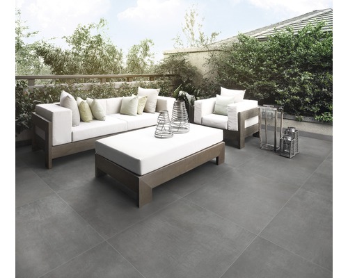 Terrass med gråa plattor, soffa, fåtölj och soffbord