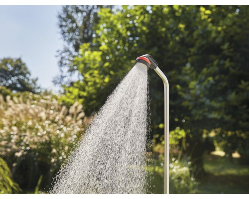 Trädgårdsdusch med rinnande vatten framför grön vegetation
