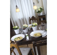 Dukat matbord med pasta, blommor och vin under pendellampor